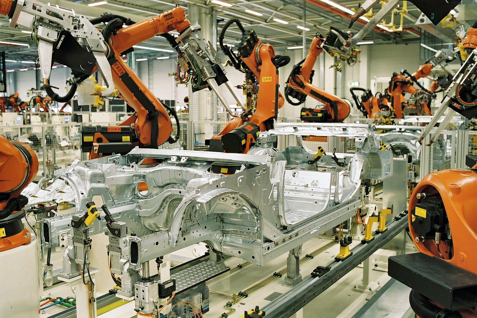 Orange industrial robots welding car bodies in a German automotive body shop